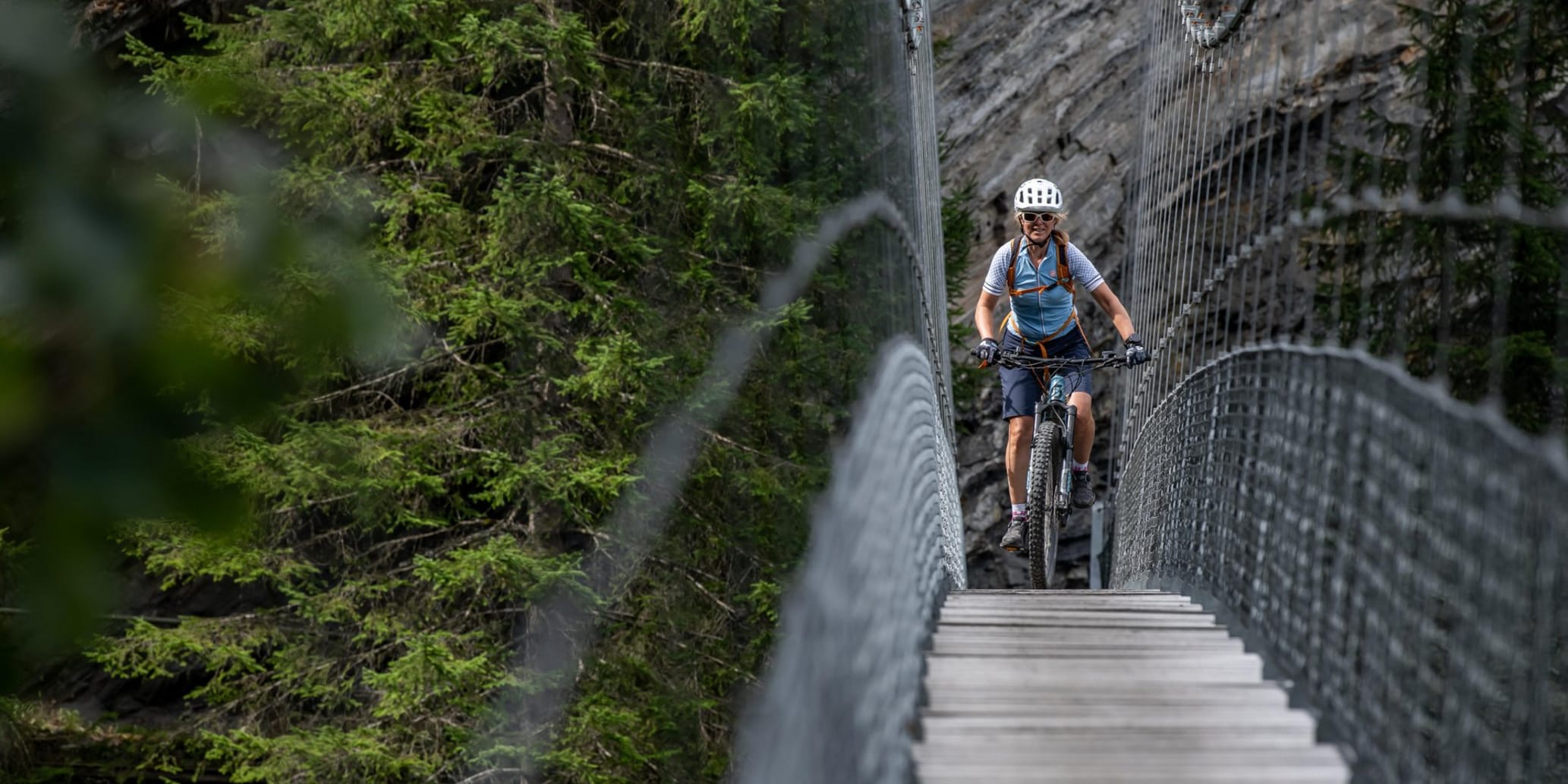 Bikerin fährt über schmale Hängebrücke