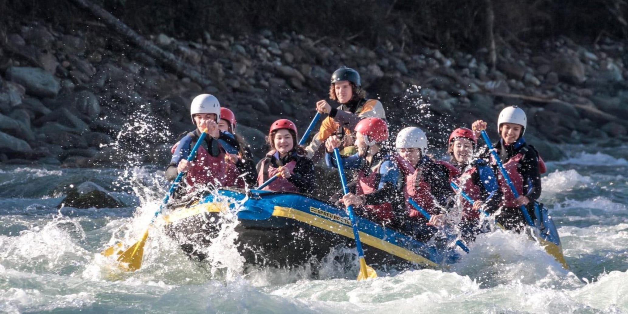 Rafting mit Schlauchboot und vielen Personen an Board auf dem Rhein