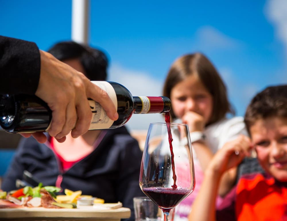 Wein wird eingeschenkt im Hintergrund Mädchen und Junge