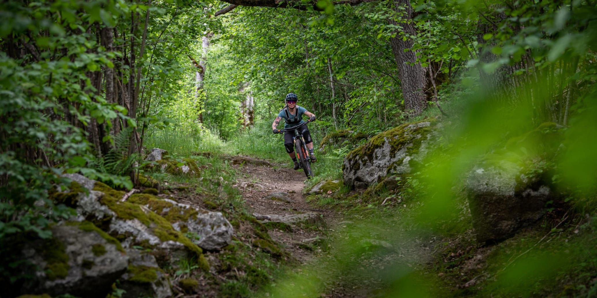 Bikerin fährt auf unebenem Waldweg auf Betrachter zu