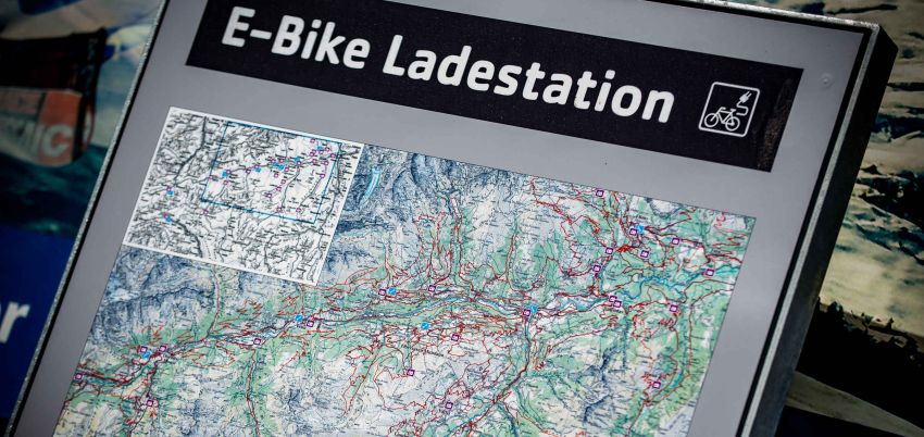Man sieht eine Tafel der E-Mountainbikeladestation mit einer Karte.